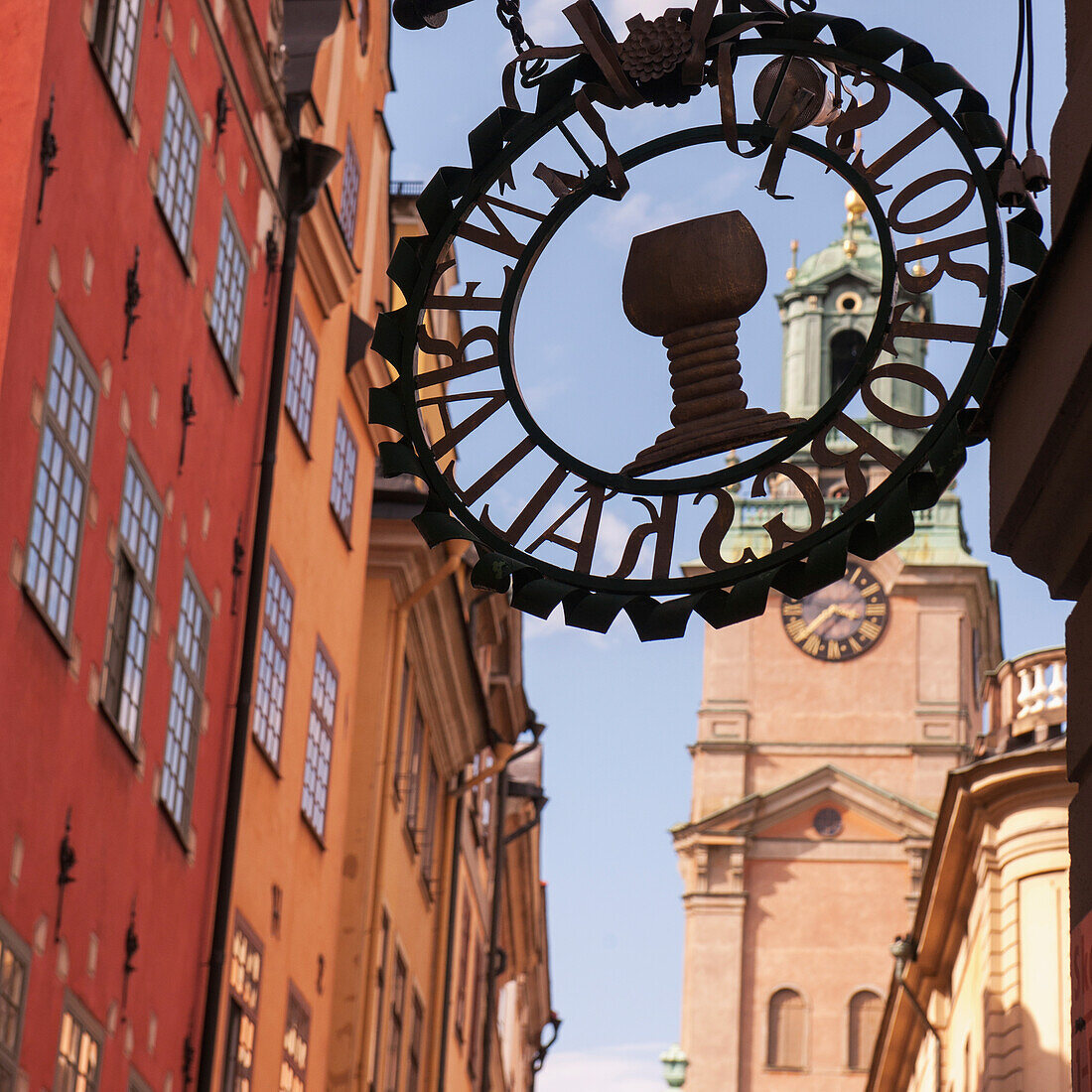 Schild an der Seite eines Gebäudes mit einem Uhrenturm im Hintergrund; Stockholm Schweden