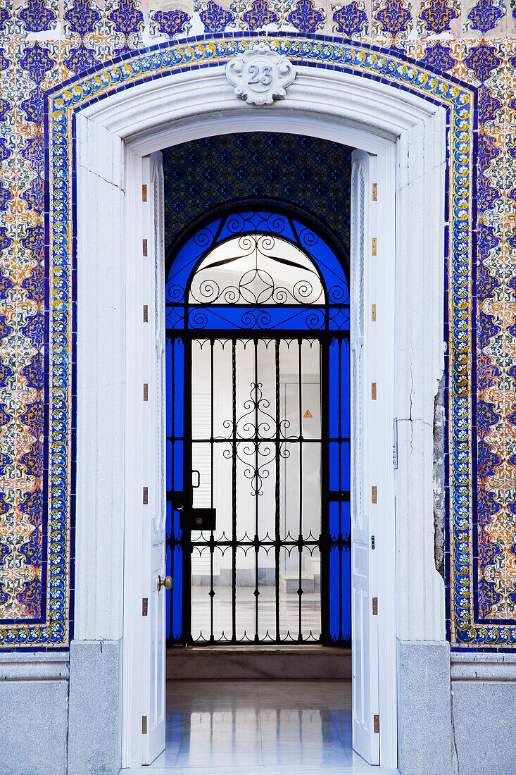 Eine offene Tür an einem Gebäude mit verzierter Fassade, die in einen Raum mit einem von blauem Glas umgebenen Tor führt; Chiclana De La Frontera Andalusien Spanien