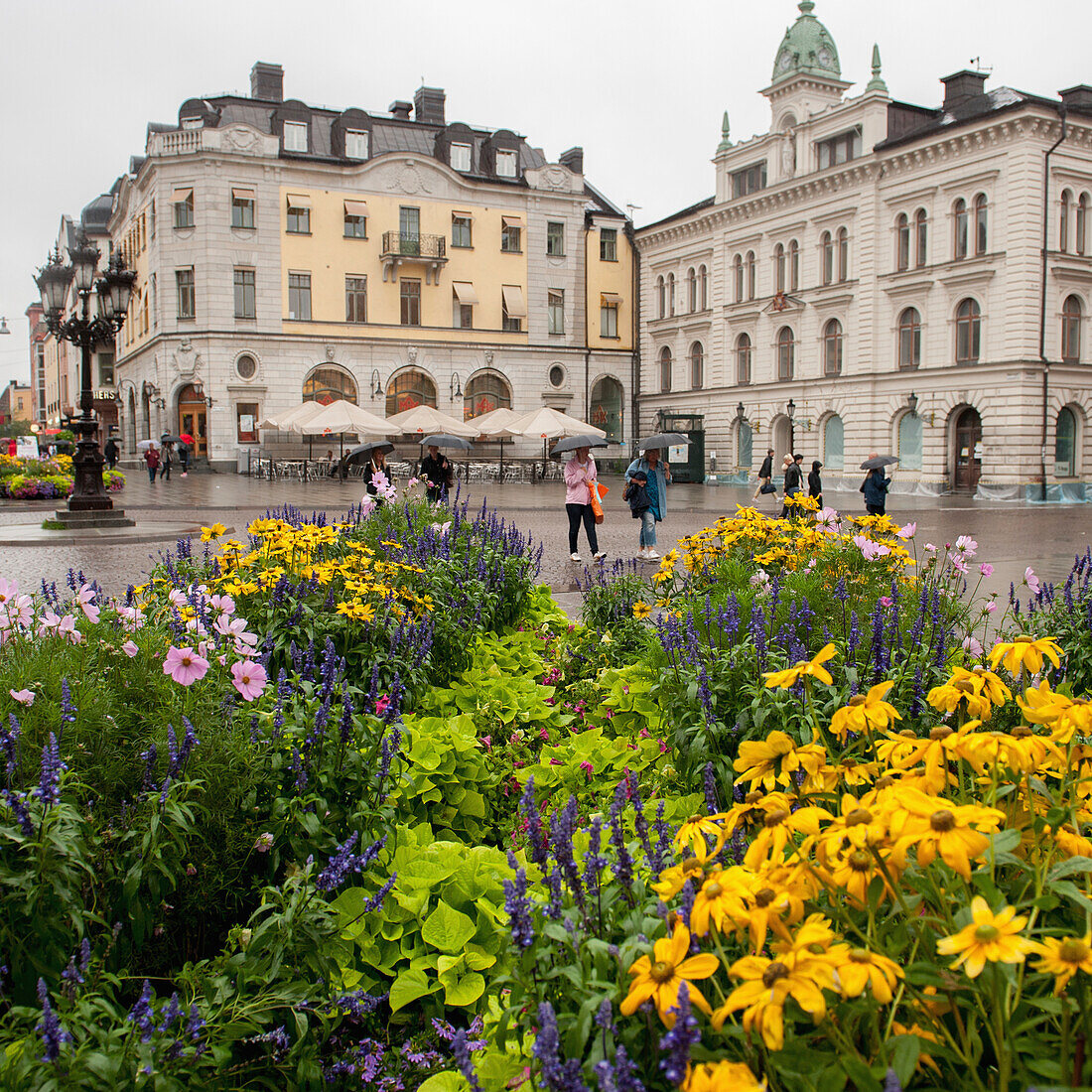 Fußgänger und farbenfrohe Blumen in einer städtischen Umgebung; Uppsala Schweden
