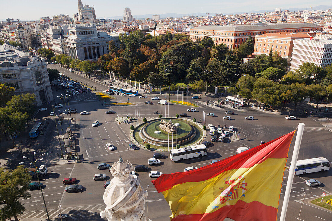 Blick über den Plaza De La Cibeles und die Calle De Alcala hinauf mit einer spanischen Flagge im Vordergrund; Madrid Spanien