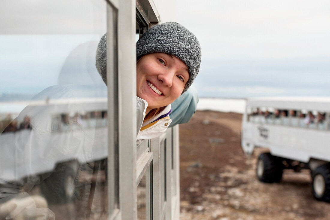 Eine junge Frau schaut aus dem Fenster eines Tundrafahrzeugs auf einer Eisbären-Expedition; Churchill Manitoba Kanada