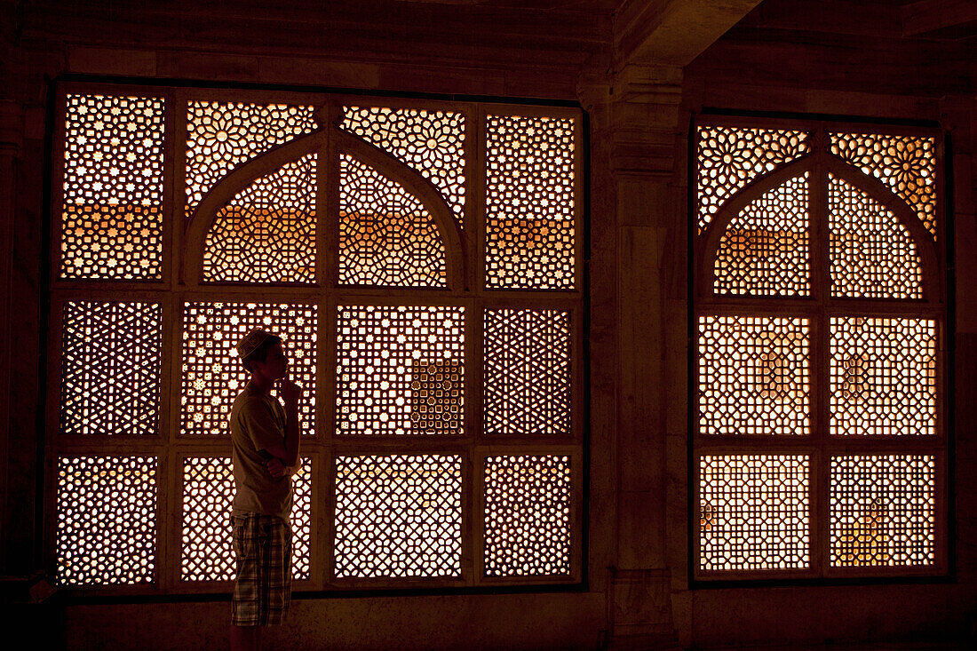 Ein junger Mann steht vor einem verschnörkelten Fenster; Jaipur Rajasthan Indien