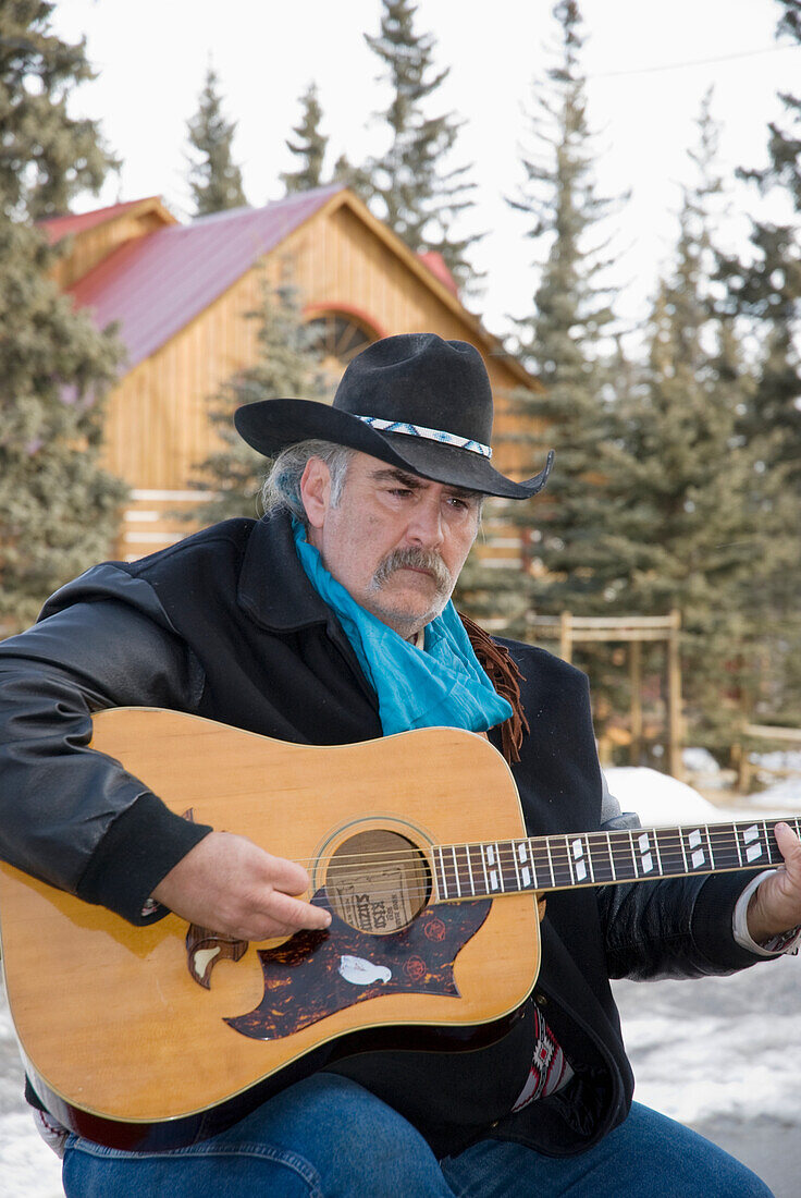 Cowboy spielt Gitarre im Freien im Winter; Bragg Creek Alberta Kanada