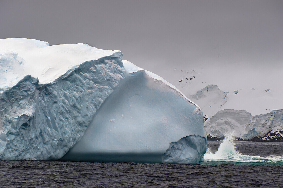 Eine Welle plätschert gegen einen Eisberg; Antarktis