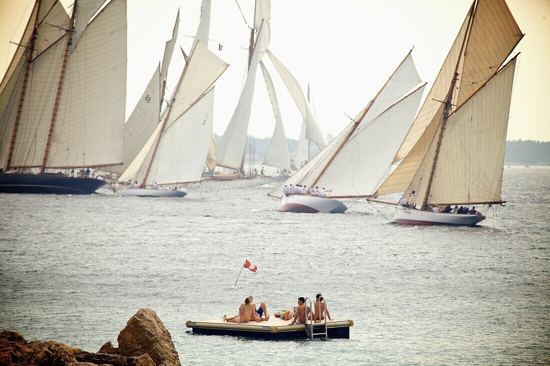 Menschen sitzen auf einem schwimmenden Dock und beobachten die Segelboote vor der Küste; Cannes Provence Frankreich