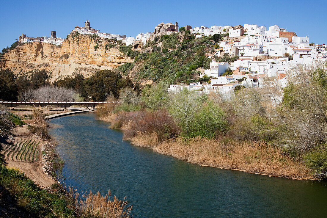 Weiß getünchte Gebäude in einer Stadt und eine Brücke, die einen Fluss überquert; Arcos De La Frontera, Andalusien, Spanien