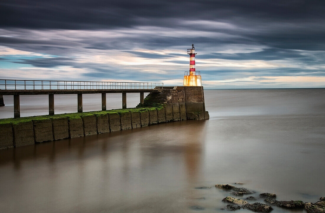 A Red And White Striped Lighthouse At The End Of A Pier; Amble Northumberland England