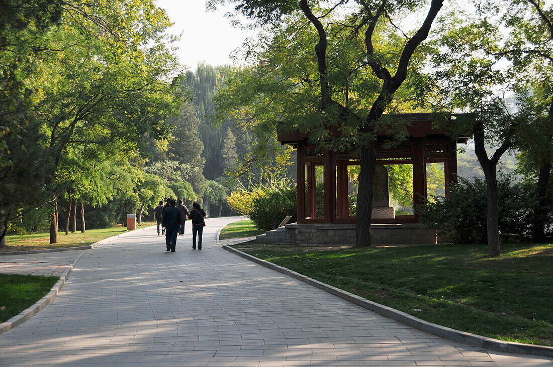 Fußgänger auf einem Gehweg durch einen Stadtpark; Beijing China