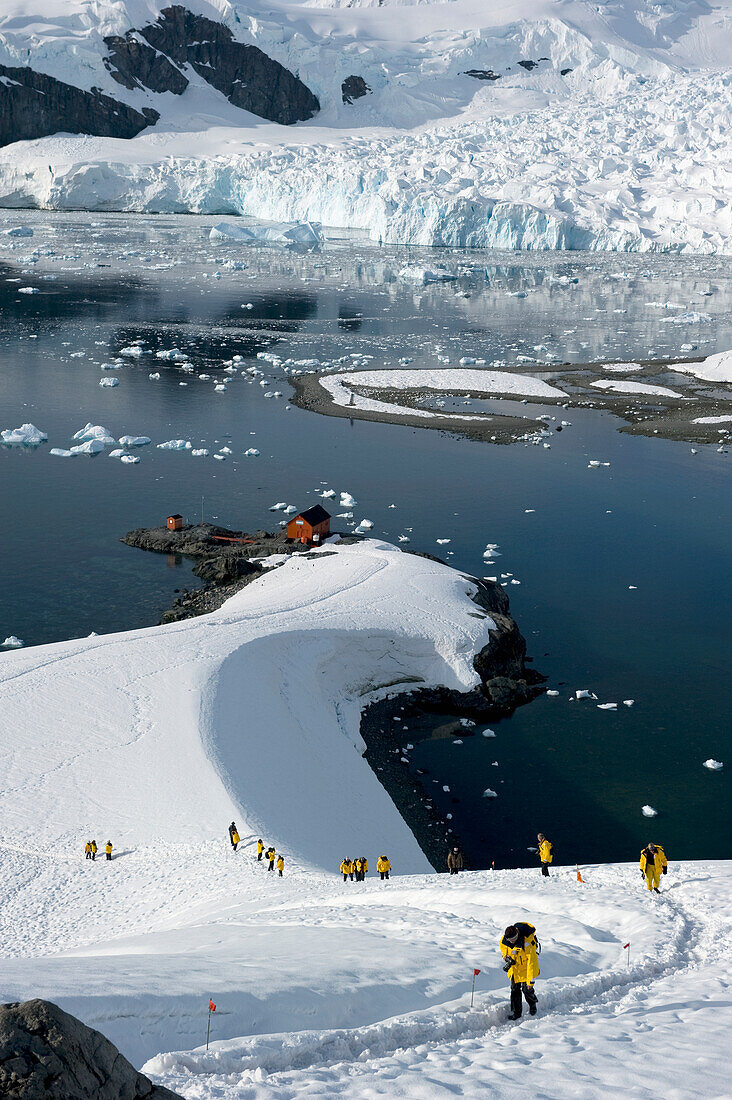 Touristen in gelben Jacken erkunden die Küste; Antarktis