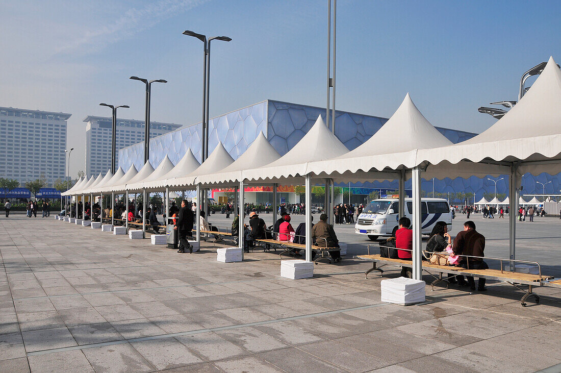 People Sitting On Benches Under White Awnings; Beijing China