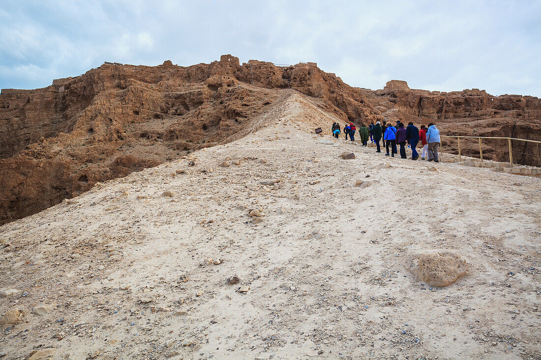 Eine Gruppe von Menschen, die einen Pfad bei der antiken Festung Masada hinaufgehen; Israel