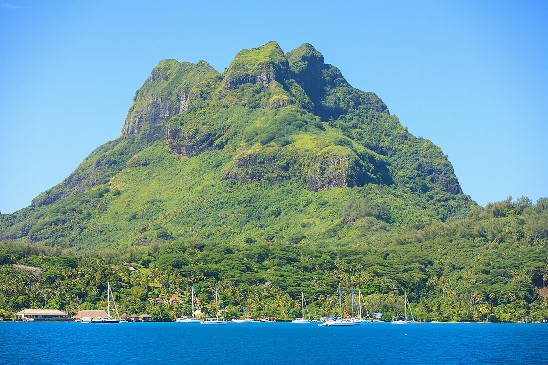 A Large Rock Formation Against A Blue Sky Along The Coast; Bora Bora Society Islands French Polynesia South Pacific