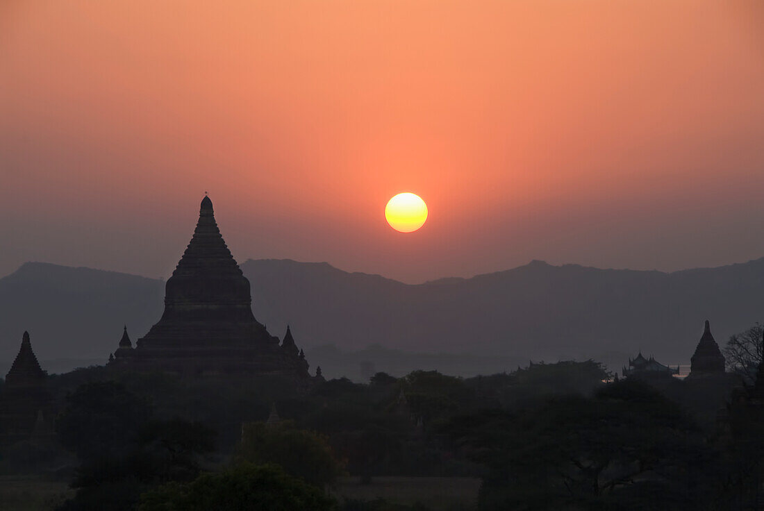Burma (Myanmar), Bagan, Silhouetted temples and sunball at sunset.