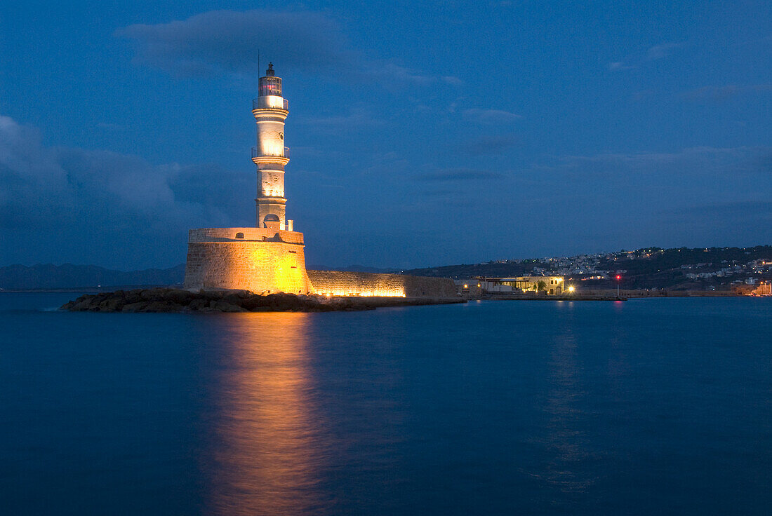 Griechenland, Kreta, Chania, Alter Leuchtturm in den Abendstunden, Lichter spiegeln sich auf dem Wasser.