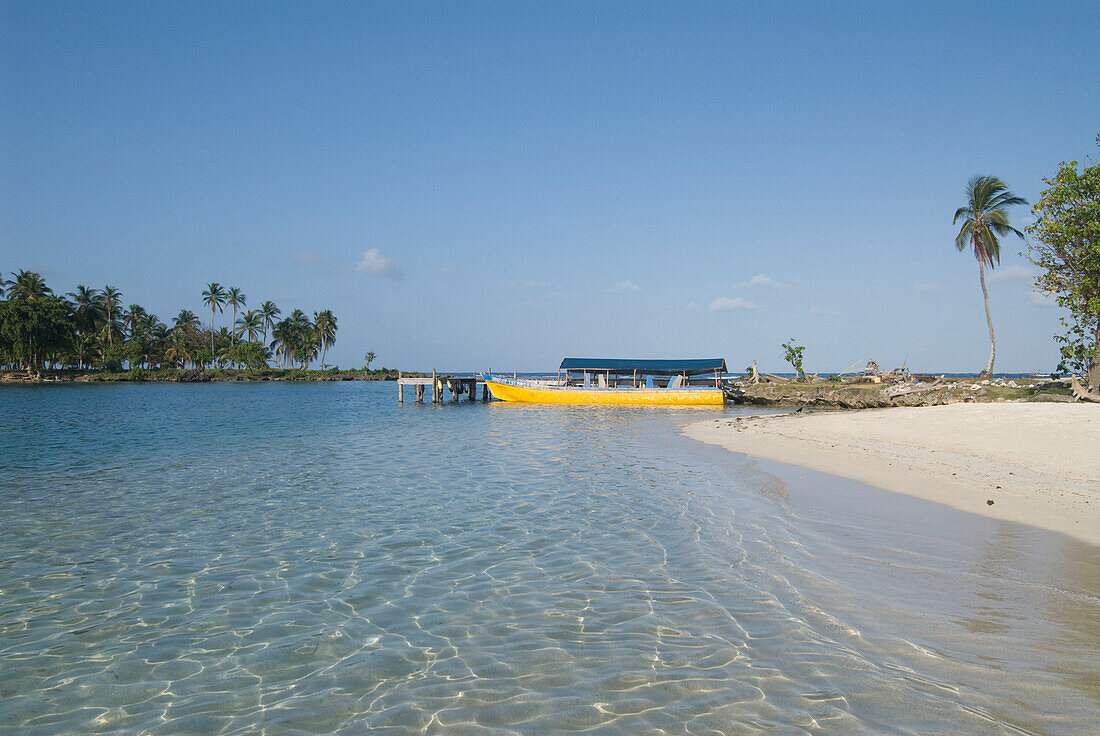 Panama, San Blas Inseln (auch Kuna Yala Inseln genannt), Yandup Insel, kleiner Strand mit Boot am Dock.