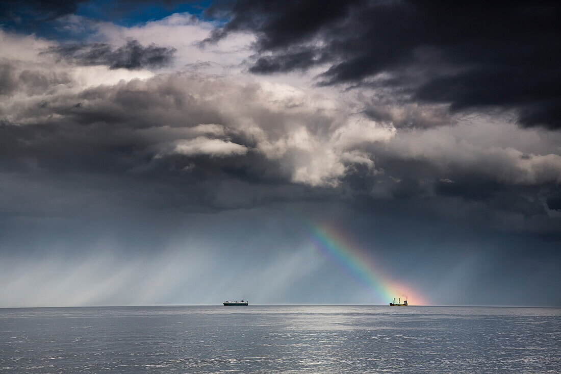 Ein Regenbogen durch Sturmwolken über einem Meer mit zwei Schiffen; Whitley Bay Northumberland England
