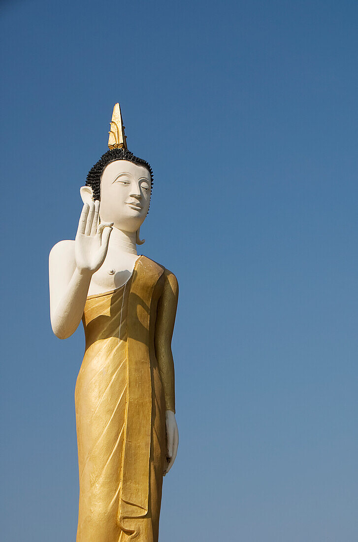 Laos, Vientiane, Wat That Luang Neua, Buddha-Statue vor blauem Himmel.