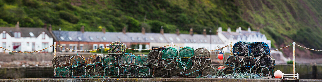 Aufgetürmte Krabbenfallen am Ufer mit Häusern im Hintergrund; Burnmouth Scottish Borders Schottland