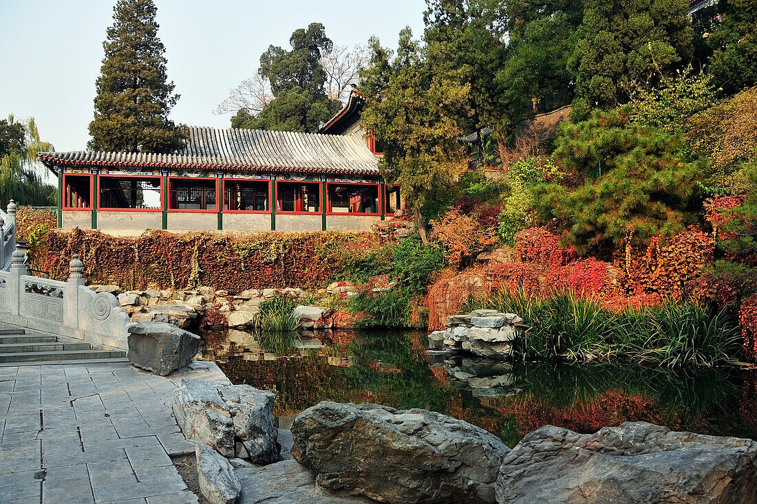 Eine überdachte Struktur in einem Park mit einem Teich; Beijing China