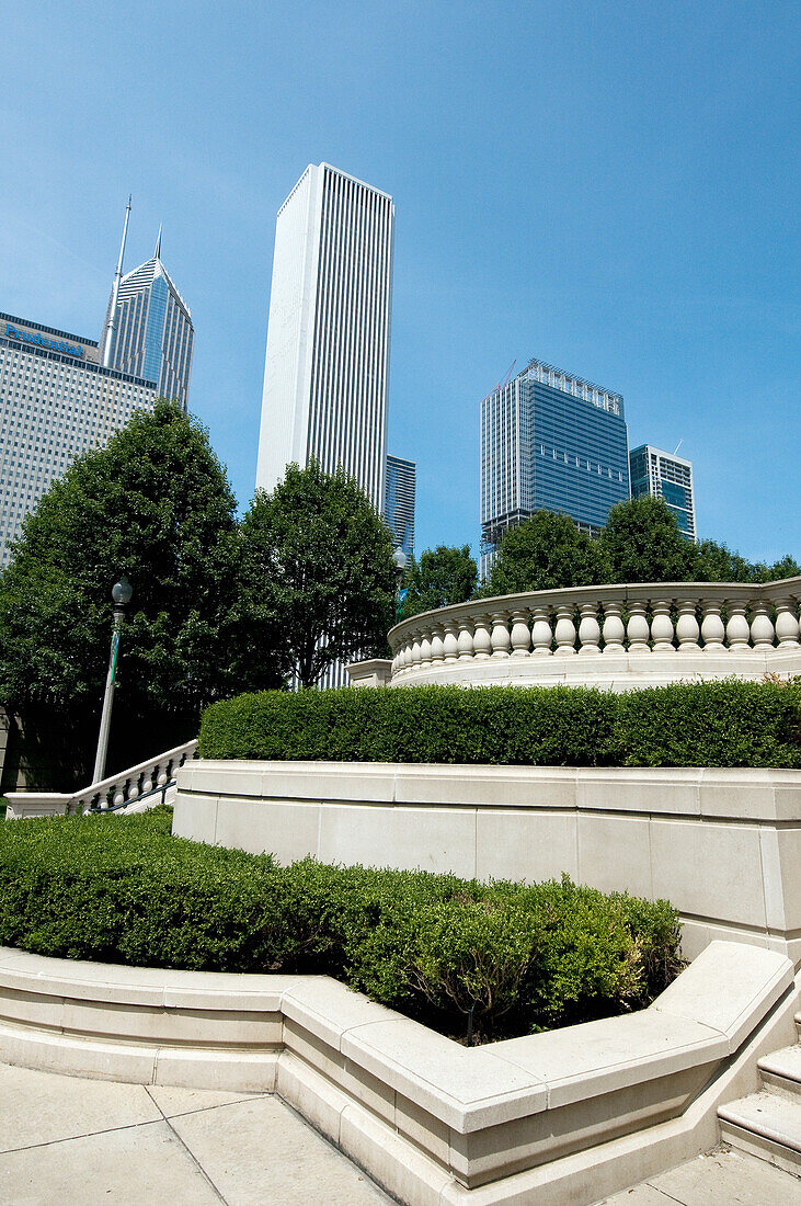 Gebäude gegen einen blauen Himmel und eine begrünte Fläche mit Sträuchern, Bäumen und Geländern; Chicago Illinois Vereinigte Staaten von Amerika