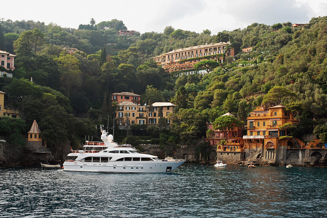 Eine im Wasser ankernde Yacht mit Wohngebäuden am Wasser; Italien