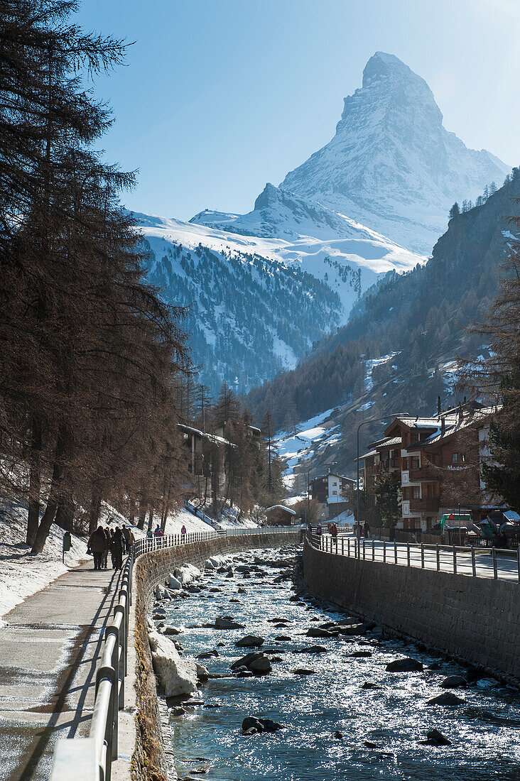 A Waterway Running Through The City With Pedestrians Walking On The Promenade; Zermatt Switzerland