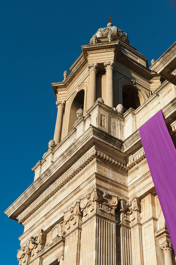 Low Angle View Of The Facade Of The Cathedral Of Guatemala City With A Purple Banner In The Front; Guatemala City Guatemala