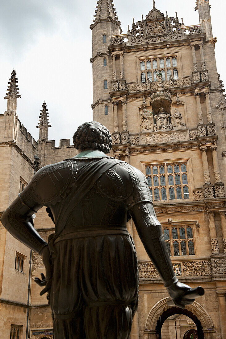 Eine Statue mit männlichem Konterfei und der Turm eines Gebäudes mit verzierter Fassade; Oxford England