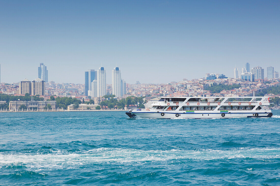 Modern buildings on the city skyline behind the dolmabahce palace with the bosphorus ferry in foreground; istanbul turkey