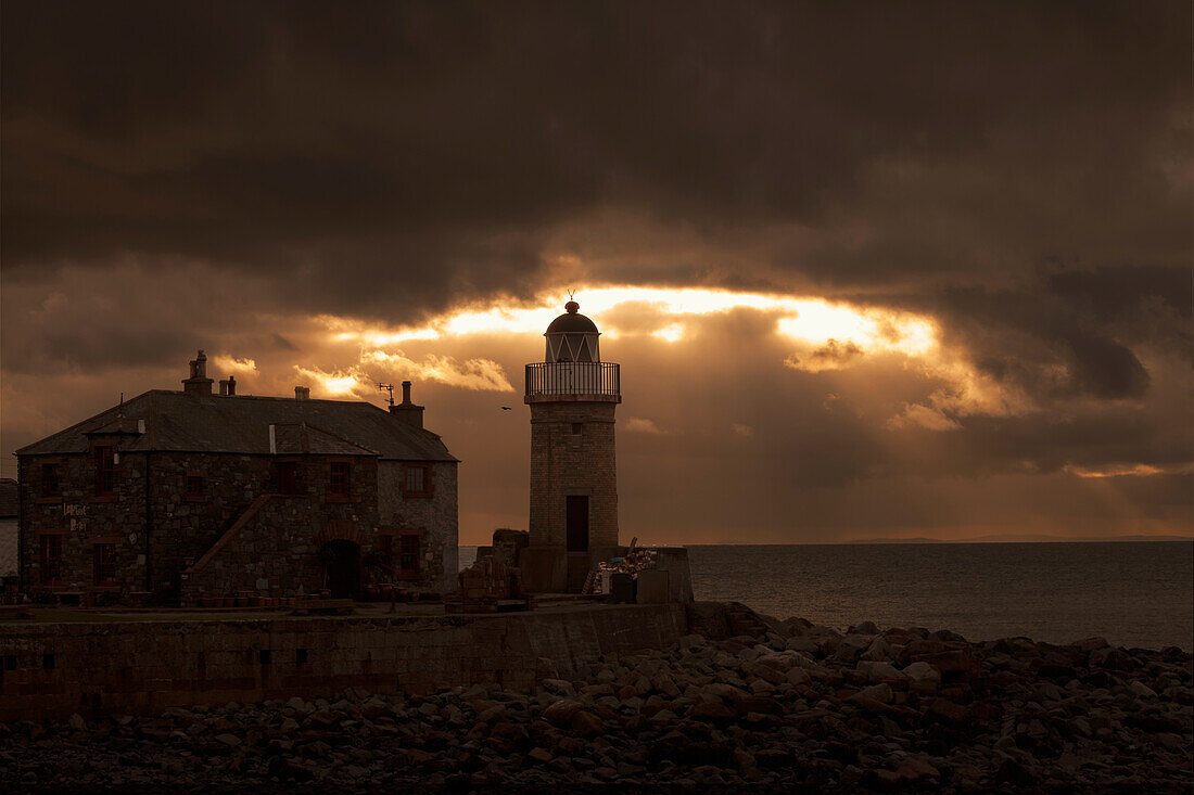 UK, Scotland, Dumfries and Galloway, Portpatrick, Lighthouse on shore and dark storm clouds