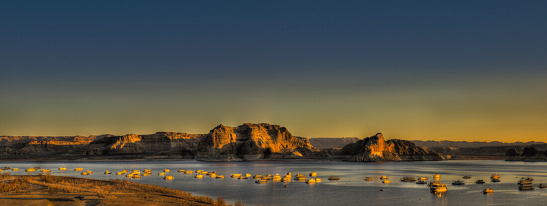 United States of America, Rocks in water and sunlight illuminating the shoreline at sunset on Powell River; Utah