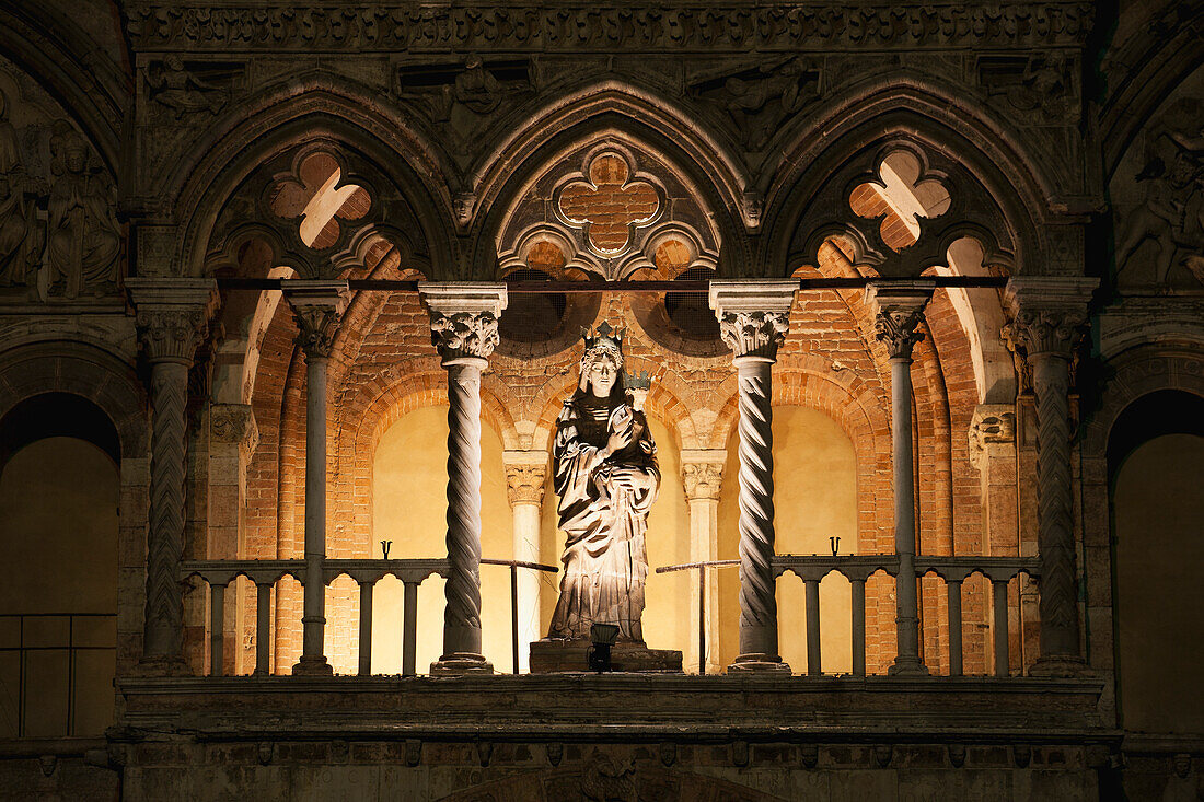 Illuminated statue in arches at night; Ferrara, Emilia-Romagna, Italy