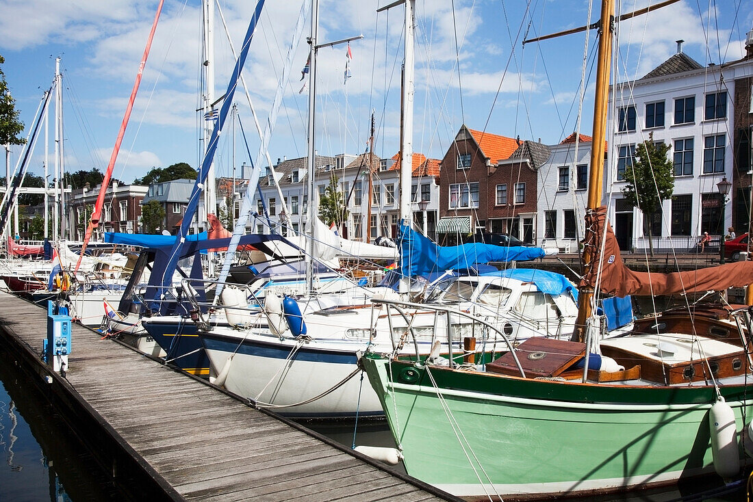 Netherlands, Zealand, Boats docked along wooden pier in harbour; Goes