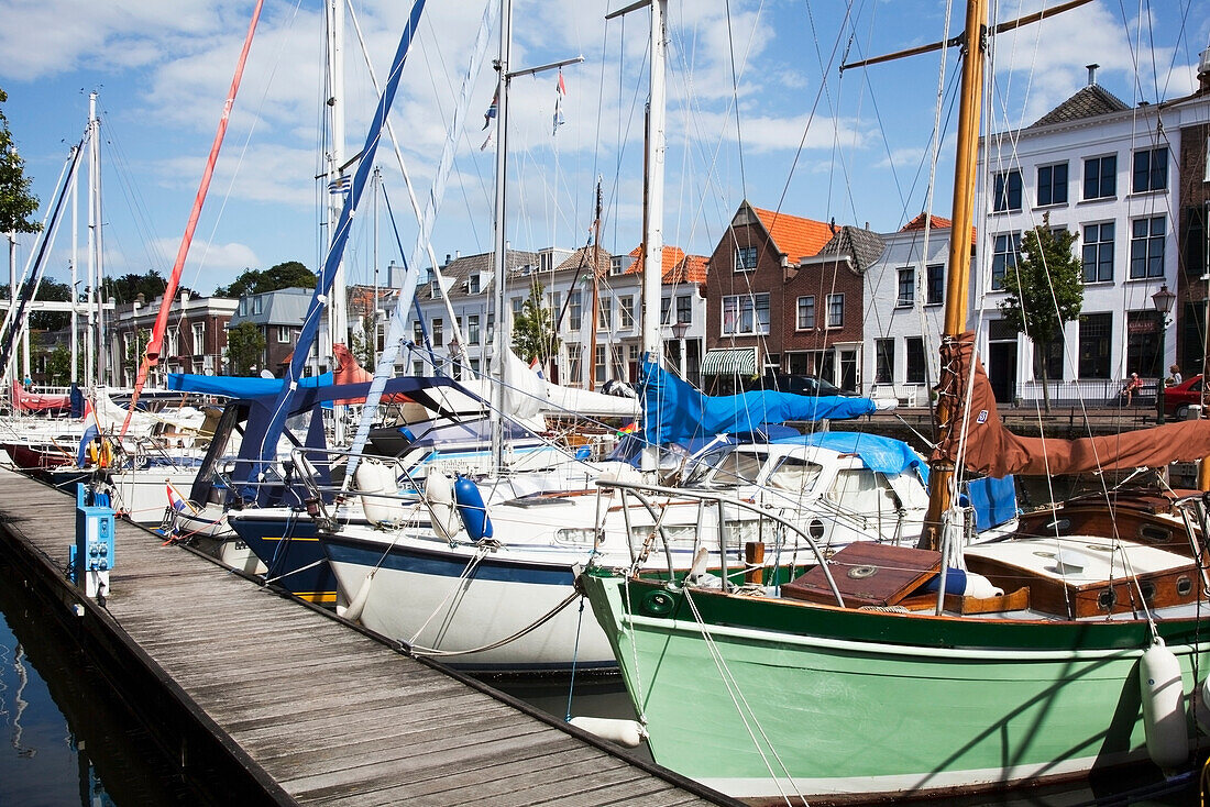 Niederlande, Seeland, Angedockte Boote entlang der hölzernen Mole im Hafen; geht