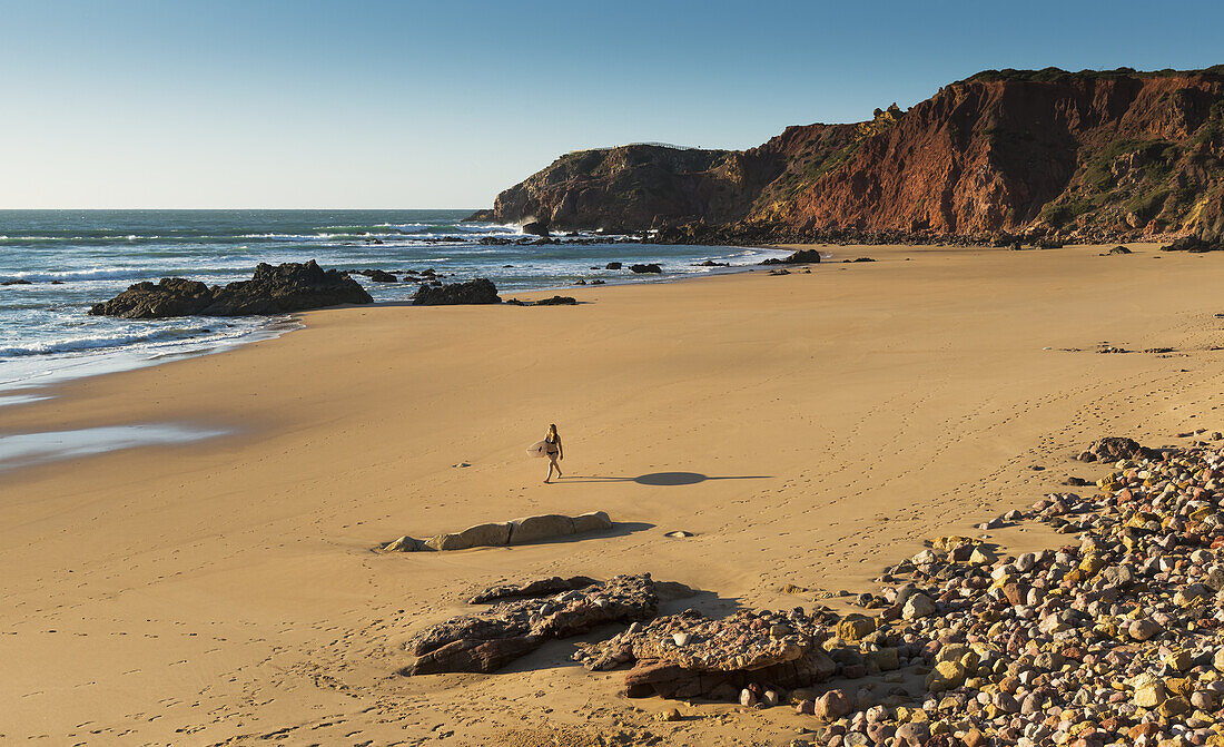 Portugal, Algarve, Fernsicht eines Surfers, der am Playa Do Amado spazieren geht; Carrapateira