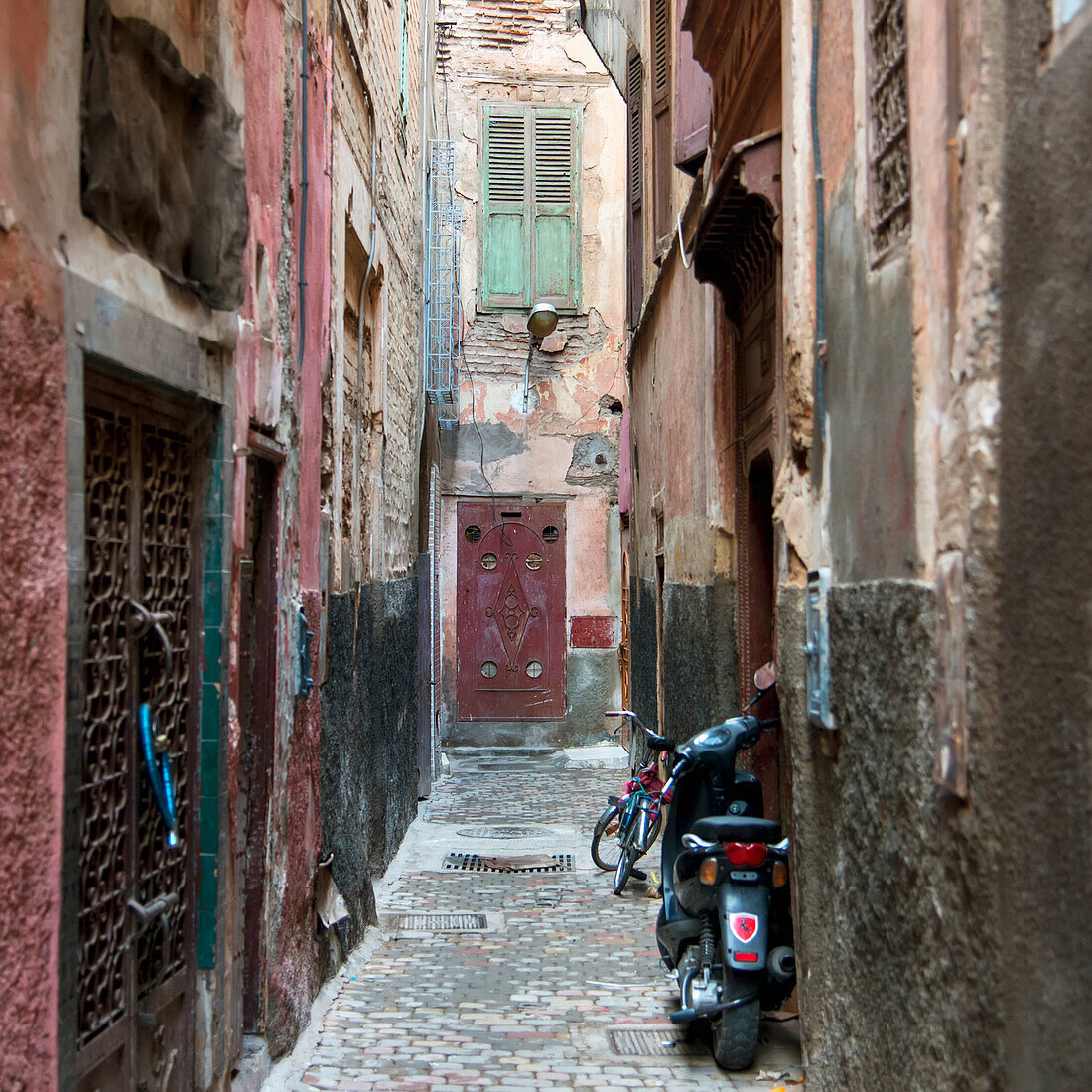 Motorrad und Fahrrad geparkt in einer engen Gasse vor einer Tür; Marrakesch, Marrakesch-Tensift-El Haouz, Marokko