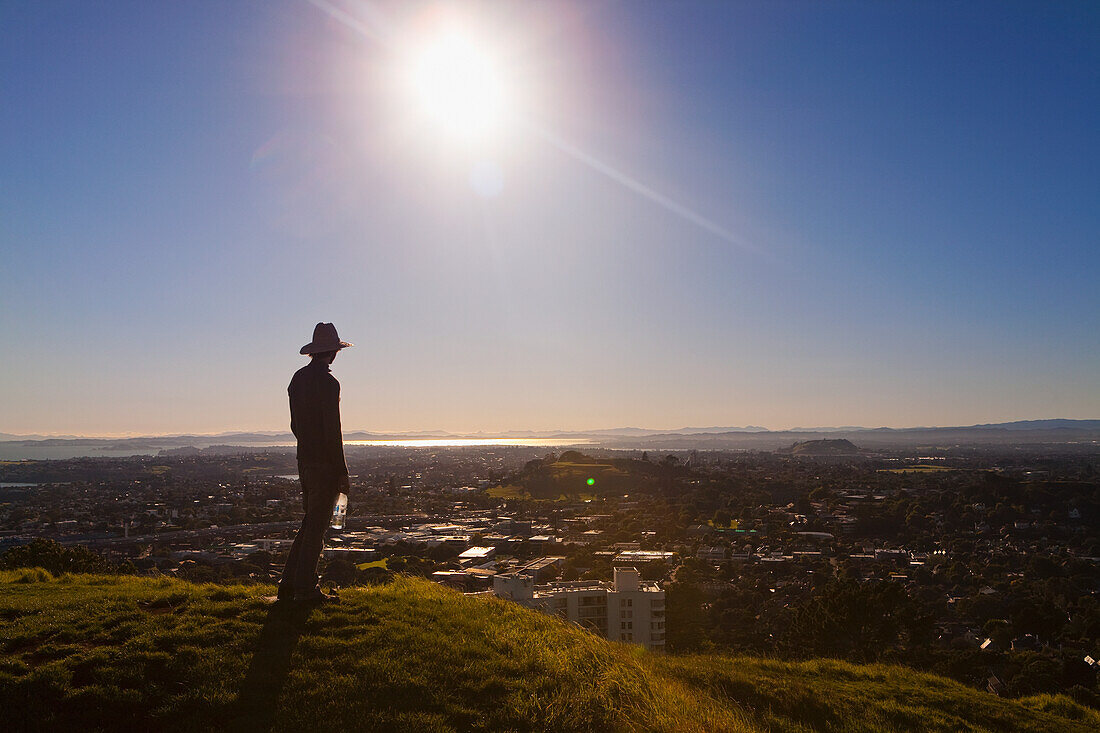 Silhouette eines Mannes mit Hut auf dem Mt. Eden mit Blick auf Auckland; Neuseeland