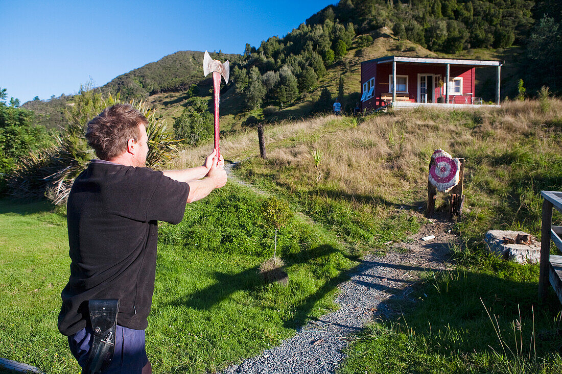 Ein Mann versucht sich an einem Axtwurf in der Blue Duck Lodge, im Whanganui National Park; Whakahoro, Neuseeland