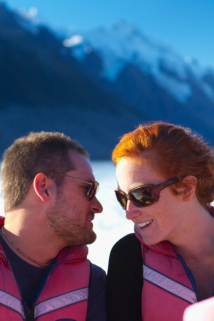 A Couple Shares A Moment As They Take A Boat Trip Through A Lake At The Base Of Mount Cook; New Zealand