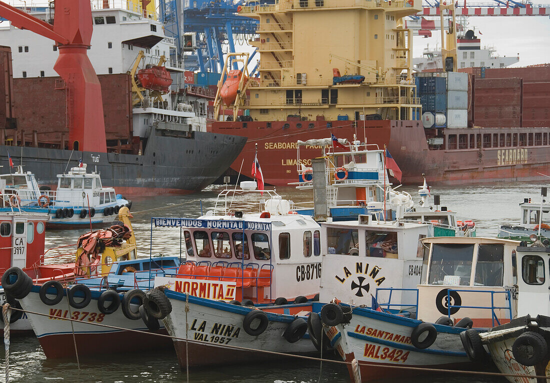 Reihe von bunten Fischerbooten im Vordergrund mit Schiffsbooten im Hintergrund; Valparaiso, Chile