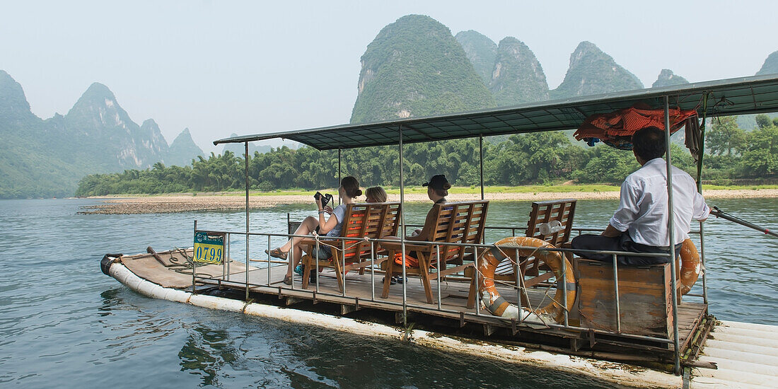 Touristen fahren auf einem Boot den Li-Fluss hinunter; Ynagshuo, Guangxi, China