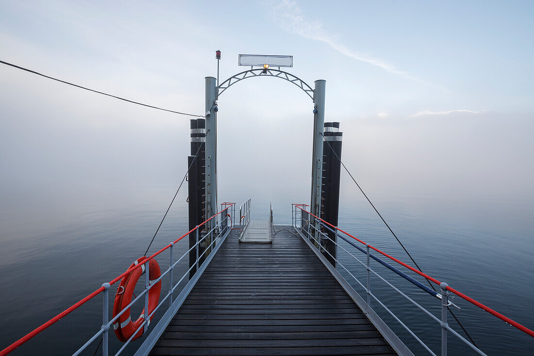 A Dock Leading Out To Fog Over Lake Maggiore; Locarno, Ticino, Switzerland