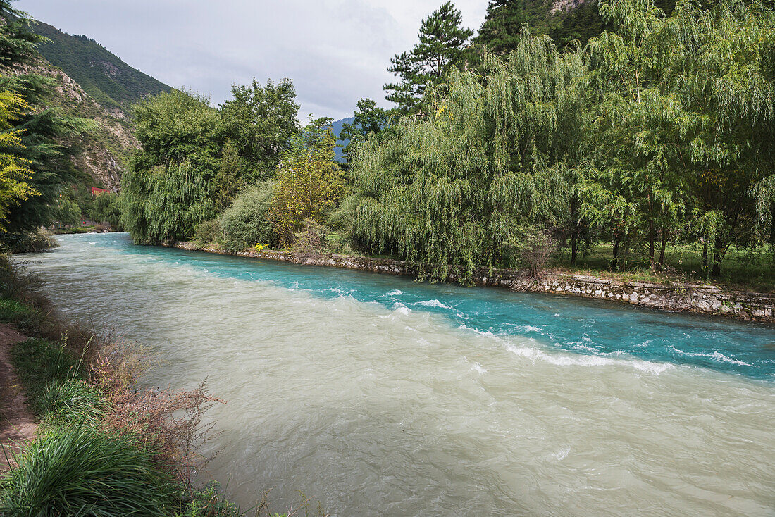 Zwei zusammenfließende Flüsse mit unterschiedlich gefärbtem Wasser in der Nähe des Eingangs zum Jiuzhaigou Valley National Park; Jiuzhaigou, Sichuan, China