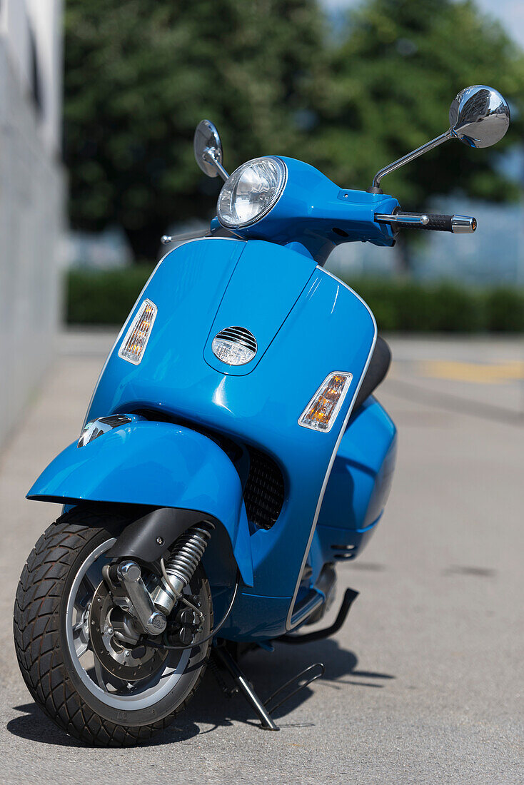 A Blue Motor Scooter Parked On The Side Of A Street; Locarno, Ticino, Switzerland