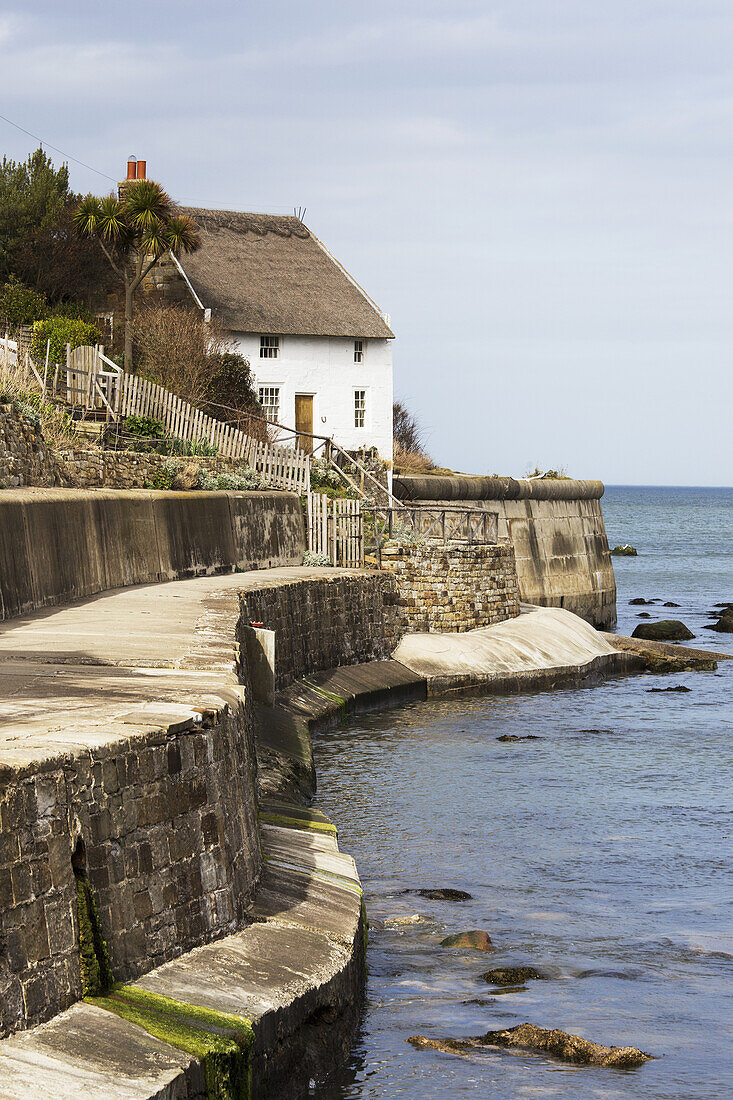 A Wall, House And Promenade Along The Water's Edge; Runswick Bay, North Yorkshire, England