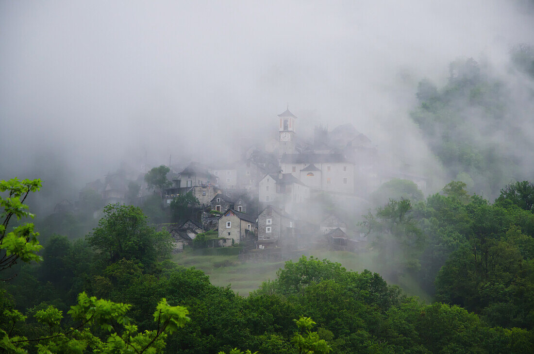 Buildings In A Village Barely Visible Through The Heavy Fog; Corippo, Ticino, Switzerland
