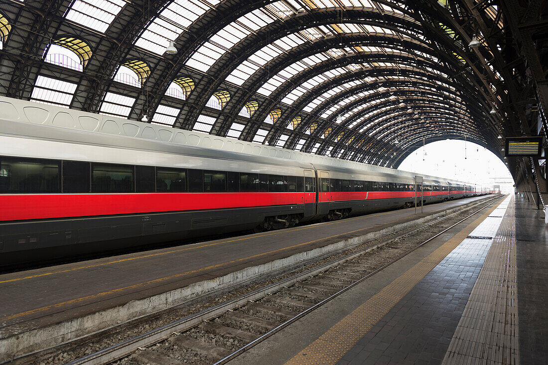 A Train On The Tracks In A Train Station With Domed Ceiling; Milan, Lombardy, Italy