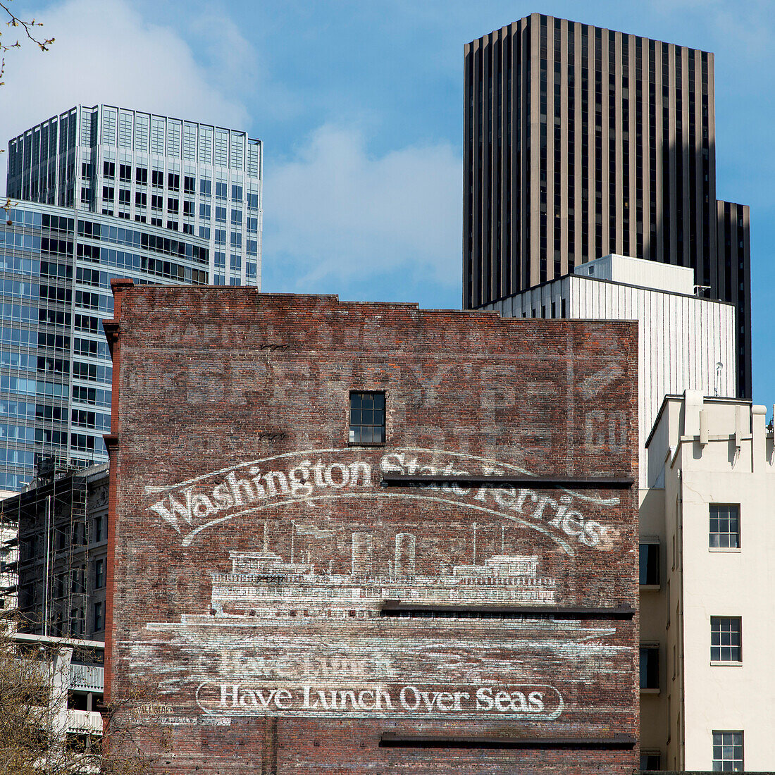 Kontrast von alten und modernen Gebäuden mit einer gemalten Werbung für Washington State Ferries; Seattle, Washington, Vereinigte Staaten Von Amerika