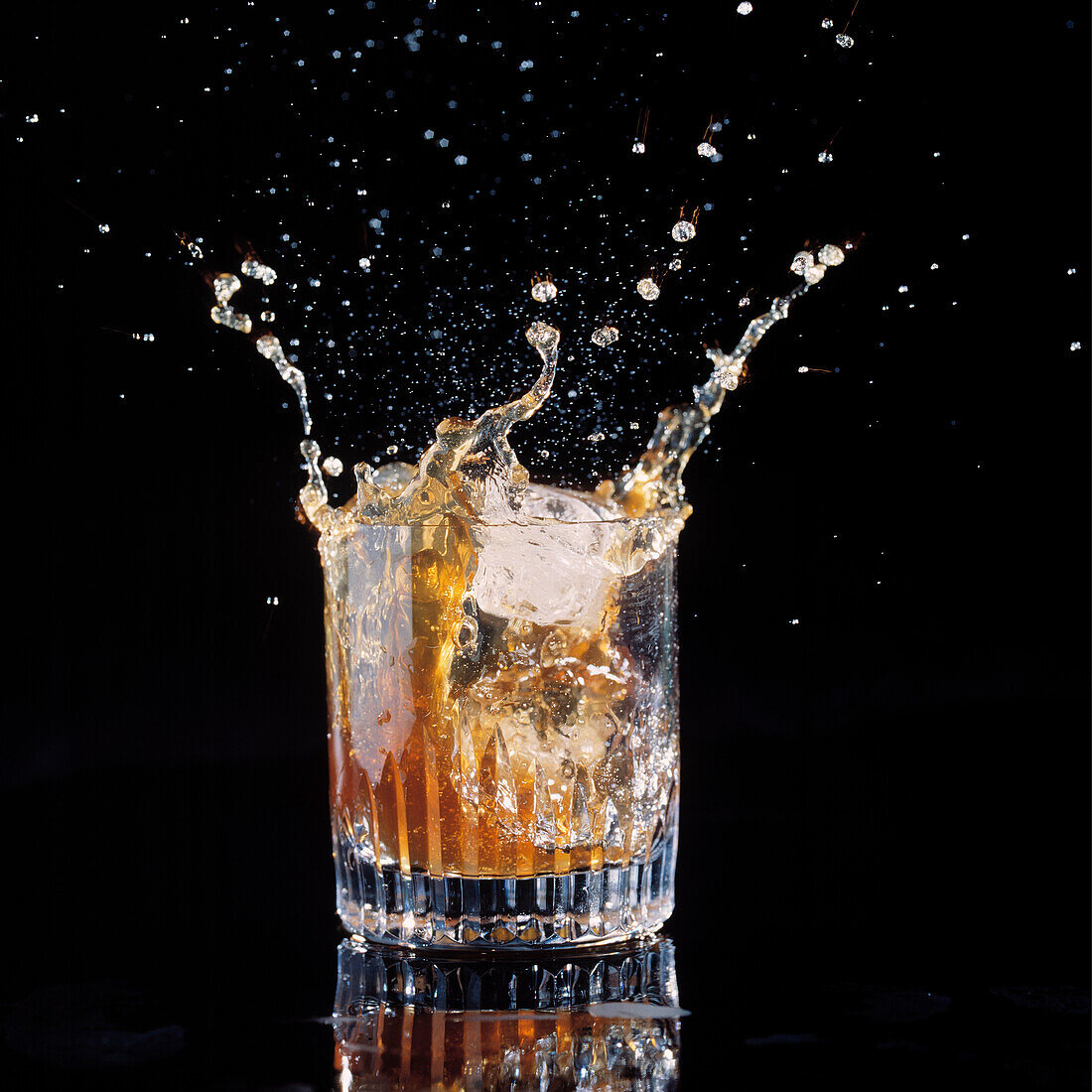 Eis spritzt in einen Becher Whiskey