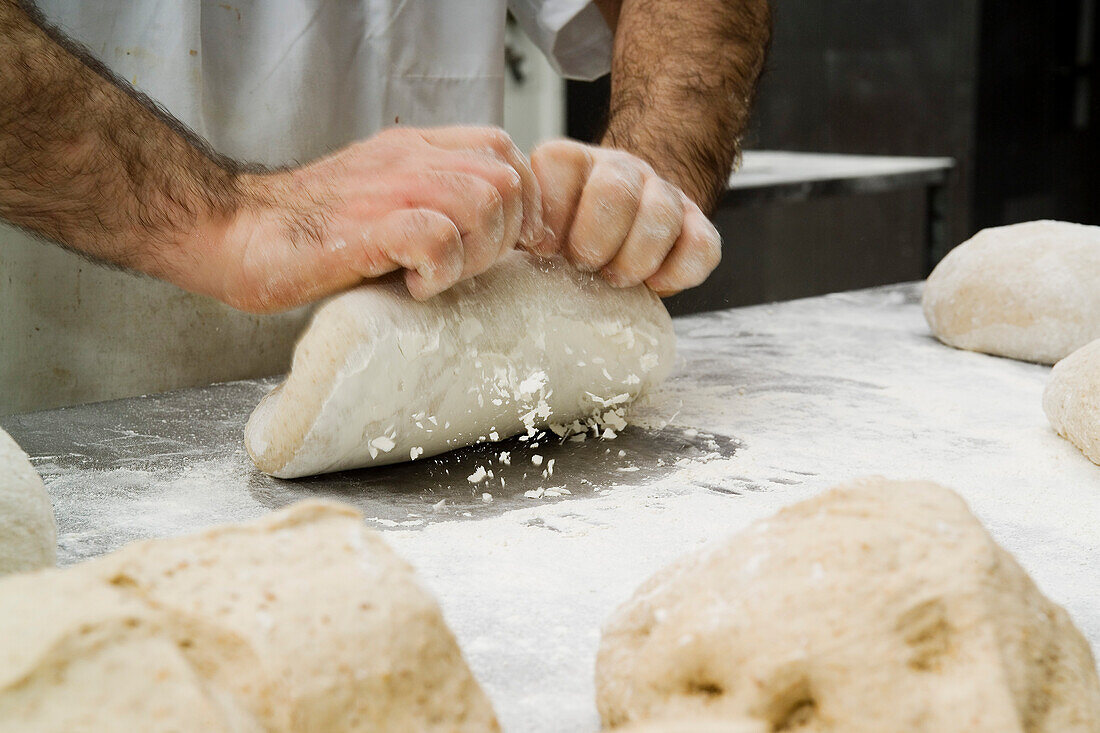 Hände des Bäckers kneten den Teig